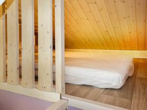 a bed in a room with a wooden wall at 5 person holiday home in BORGHOLM in Borgholm