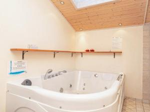 uma banheira na casa de banho com tecto em madeira em 6 person holiday home in Ringk bing em Ringkøbing