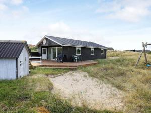 a black house with a deck on the beach at 8 person holiday home in Ringk bing in Ringkøbing