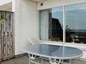 un tavolo in vetro su un patio con finestra di 4 person holiday home in R m a Rømø Kirkeby