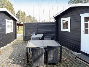 a patio with a table and chairs next to a black wall at 6 person holiday home in R dby in Rødby