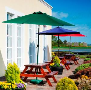 two picnic tables with umbrellas on a patio at Park Inn by Radisson Shannon Airport in Shannon