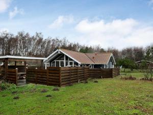 a house behind a wooden fence in a field at Three-Bedroom Holiday home in Rødby 30 in Kramnitse