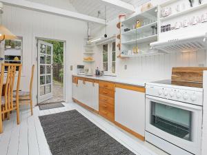La cuisine est équipée de placards blancs et d'un four avec plaques de cuisson. dans l'établissement 6 person holiday home in R dby, à Rødby