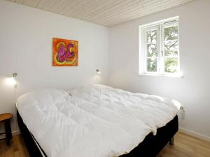 a bedroom with a large white bed with a window at Holiday Home Den II in Læsø