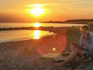 un hombre sentado en la playa viendo la puesta de sol en 6 person holiday home in R dby, en Rødby