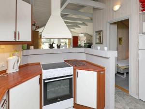 eine Küche mit weißen Schränken und einem Herd mit Backofen in der Unterkunft 8 person holiday home in Bl vand in Blåvand