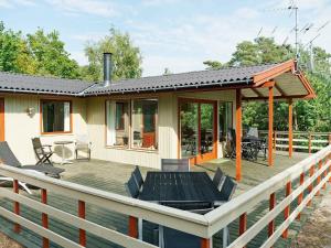 Vester Sømarkenにある6 person holiday home in Aakirkebyのデッキ(テーブル、椅子付)が備わる家