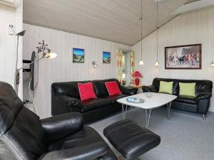 ブラーバンドにある8 person holiday home in Bl vandのリビングルーム(黒革の家具、テーブル付)