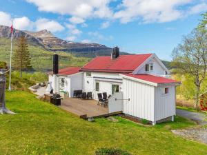 Cabaña blanca con terraza y montañas al fondo en 8 person holiday home in Inndyr, en Inndyr