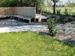 un banco de madera sentado en el césped junto a una valla en 12 person holiday home in Nordborg, en Nordborg