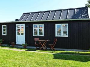 a black house with two chairs and a table in front of it at Holiday home in Skagen 4 in Skagen