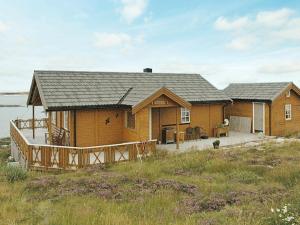 a large wooden house with a deck in a field at Three-Bedroom Holiday home in Dyrvik in Tuvnes