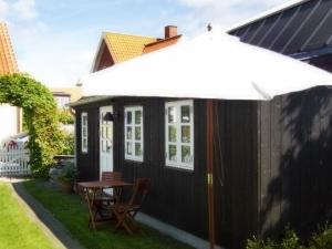 a black tiny house with a table and an umbrella at 4 person holiday home in Skagen-By Traum in Skagen