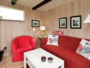Tørresøにある4 person holiday home in Otterupのリビングルーム(赤いソファ、赤い椅子付)