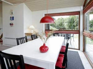 6 person holiday home in Hirtshals في هيرتسهلس: غرفة طعام مع طاولة بيضاء ومصباح احمر