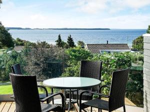 エーベルトフトにある8 person holiday home in Ebeltoftのテーブルと椅子、水辺の景色を望むバルコニー
