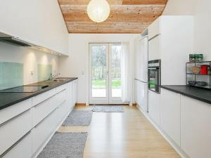 Slettestrandにある10 person holiday home in Fjerritslevの白いキャビネットと木製の天井が備わるキッチン