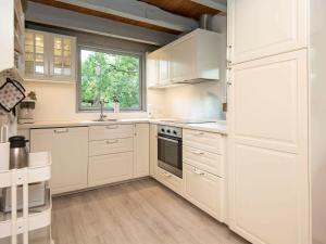 une cuisine blanche avec des placards blancs et une fenêtre dans l'établissement 5 person holiday home in Ebeltoft, à Øksenmølle