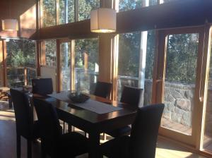 ein Esszimmer mit einem Tisch, Stühlen und Fenstern in der Unterkunft Maria del Bosque Apart Hotel / Cabañas in San Carlos de Bariloche