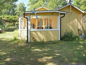 ein kleines Haus mit einem großen Fenster im Hof in der Unterkunft One-Bedroom Holiday home in Hästveda in Lur