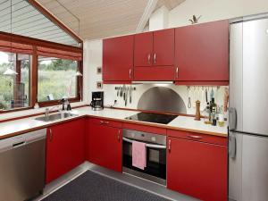 ヒアツハルスにある6 person holiday home in Hirtshalsのキッチン(赤いキャビネット、ステンレス製の冷蔵庫付)
