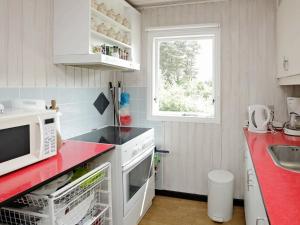 uma cozinha com electrodomésticos brancos e uma bancada vermelha em Three-Bedroom Holiday home in Hals 38 em Hals