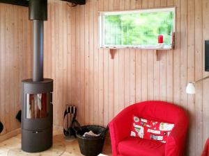 Tørresøにある4 person holiday home in Otterupのリビングルーム(赤い椅子、薪ストーブ付)