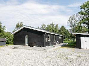 a black cabin with a dog sitting outside of it at 7 person holiday home in Jægerspris-By Traum in Jægerspris