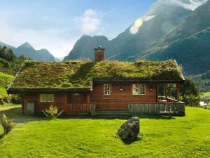 una baita di tronchi con tetto in erba su un campo verde di Four-Bedroom Holiday home in Olden 2 a Olden