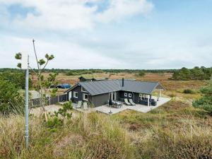 uma casa com um telhado cinzento no topo de um campo em 8 person holiday home in R m em Bolilmark