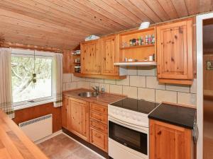 a kitchen with wooden cabinets and a stove and a window at 8 person holiday home in N rre Nebel in Lønne Hede