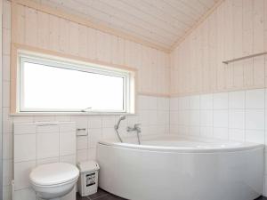 a bathroom with a tub and a toilet and a window at 10 person holiday home in Gro enbrode in Großenbrode