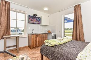 a bedroom with a bed and a kitchen with a window at Karkle Beach Suites in Karklė