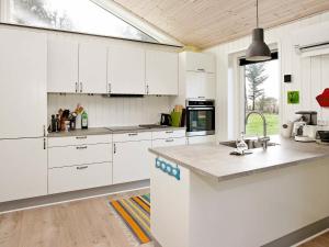 KnudにあるThree-Bedroom Holiday home in Spøttrup 11の白いキャビネットと大きな窓付きのキッチン