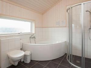 ein weißes Bad mit einer Badewanne und einem WC in der Unterkunft 8 person holiday home in Gro enbrode in Großenbrode