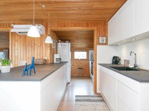 cocina con armarios blancos y paredes de madera en 5 person holiday home in S by, en Saeby