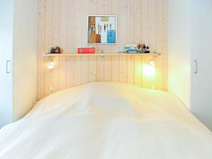 TranekærにあるHoliday home Tranekær IVの白いベッド1台(木製ヘッドボード付)が備わるベッドルーム1室が備わります。