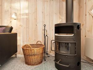 a wood stove in a room with a basket at 6 person holiday home in Oksb l in Oksbøl