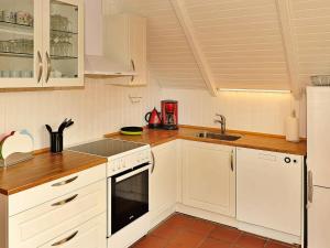una cocina con armarios blancos y fregadero en Three-Bedroom Holiday home in Nørre Nebel 16, en Lønne Hede