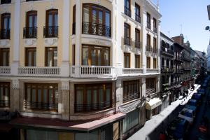 un edificio con balcones y coches aparcados en una calle en Madrisol en Madrid