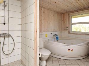 y baño con bañera, aseo y lavamanos. en 10 person holiday home in Fan en Fanø