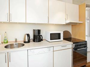 a kitchen with white cabinets and a sink and a microwave at 4 person holiday home in Vejers Strand in Vejers Strand