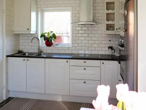 een keuken met witte kasten, een wastafel en een raam bij 4 person holiday home in FALKENBERG in Falkenberg