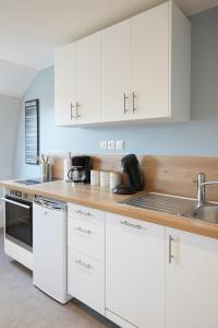 a kitchen with white cabinets and a sink at LocationsTourcoing - Le Famelart in Tourcoing