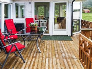 een afgeschermde veranda met rode stoelen en een glazen tafel bij 11 person holiday home in kolvereid in Kolvereid