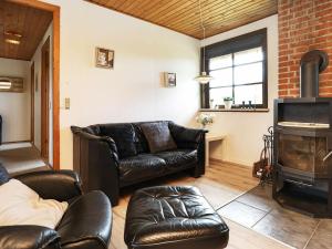 a living room with leather furniture and a fireplace at 6 person holiday home in Bl vand in Blåvand