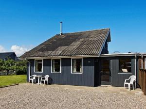 a blue house with white chairs in front of it at Three-Bedroom Holiday home in Hemmet 89 in Falen