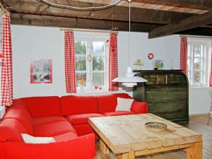 ブラーバンドにある5 person holiday home in Bl vandのリビングルーム(赤いソファ、木製テーブル付)