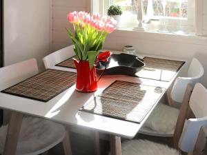 een tafel met een rode vaas met roze bloemen erop bij 4 person holiday home in FALKENBERG in Falkenberg